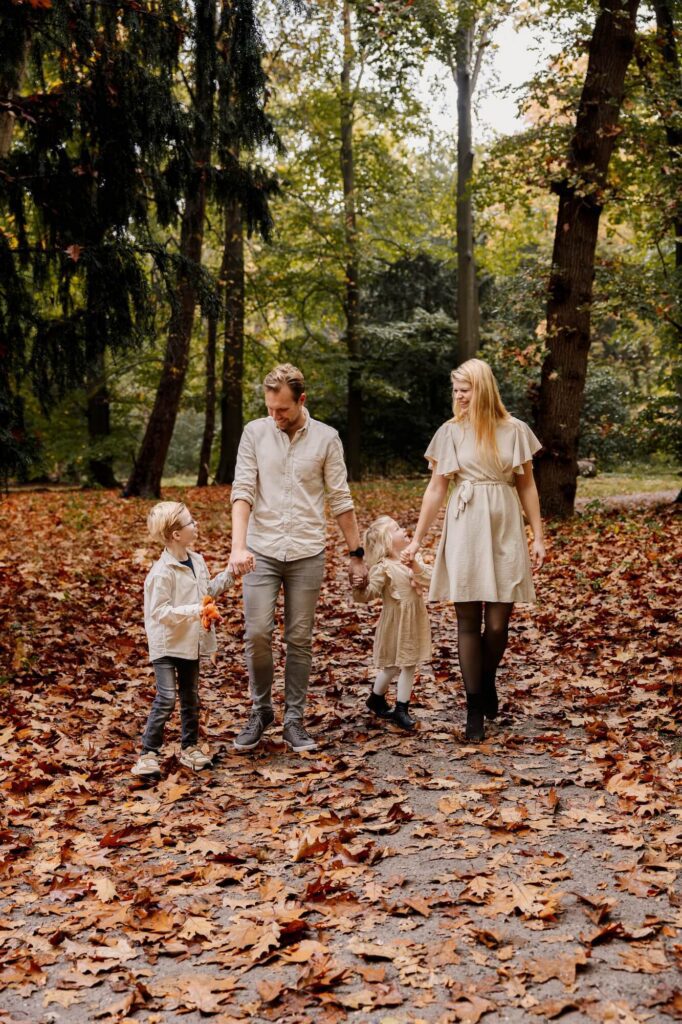 Gezin draagt matching outfits tijdens familie fotoshoot in het bos tijdens de herfst