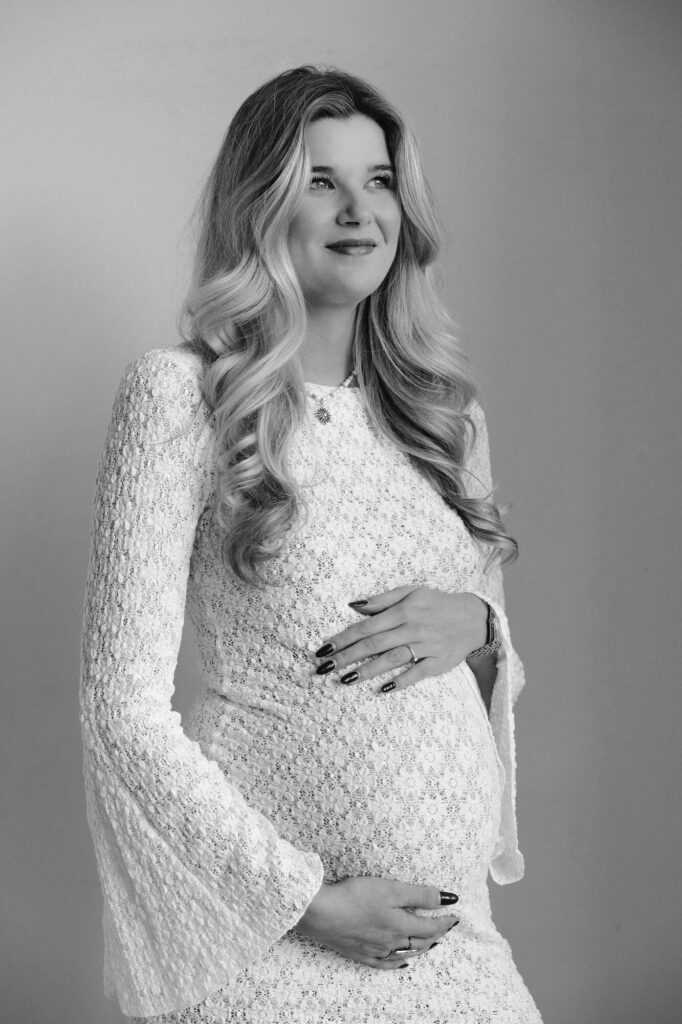 Zwart-wit foto van zwangere vrouw in kanten jurk in daglicht studio Atelier Oost in Amsterdam