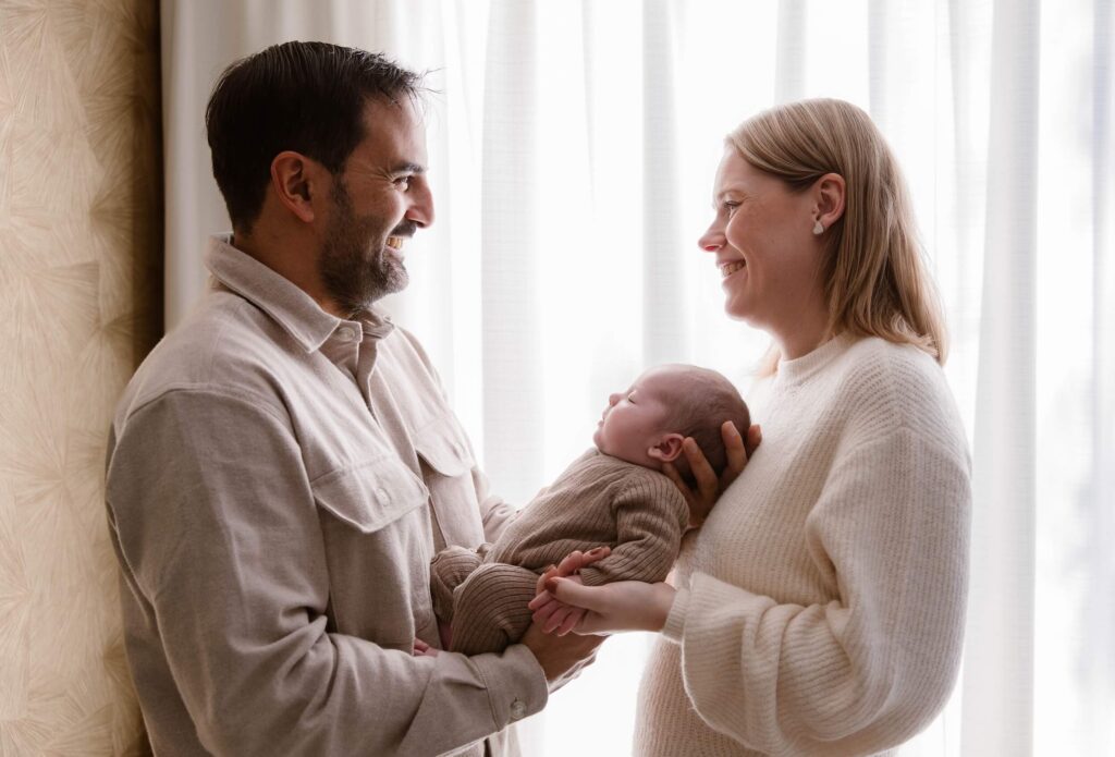 Ouders kijken liefdevol naar elkaar terwijl ze pasgeboren baby vasthouden