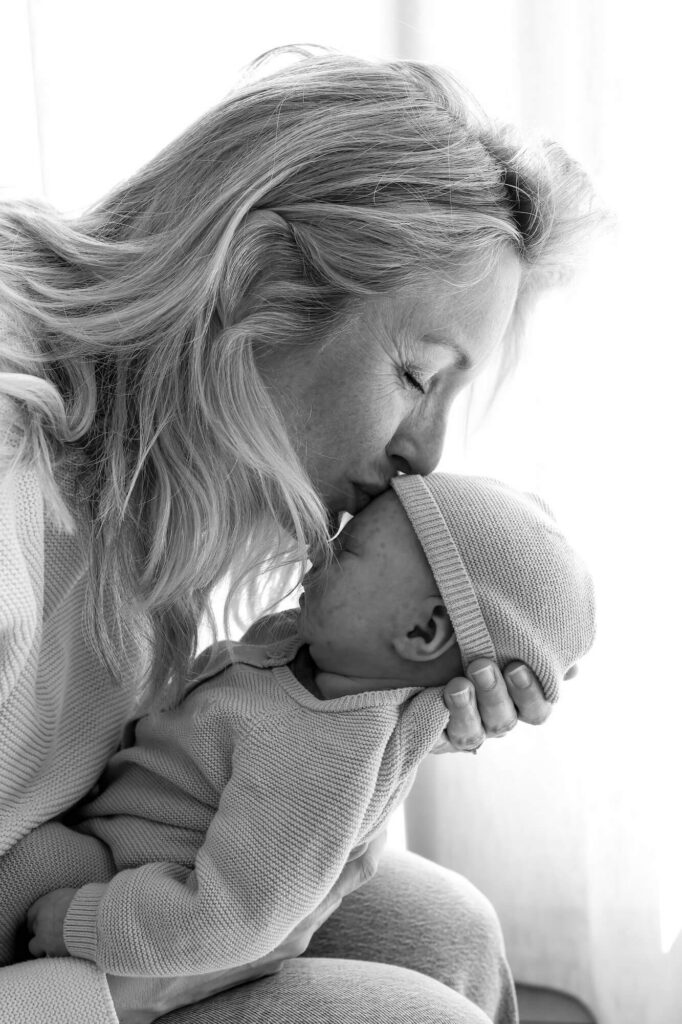 Mama geeft slapende baby een zoen op het voorhoofd