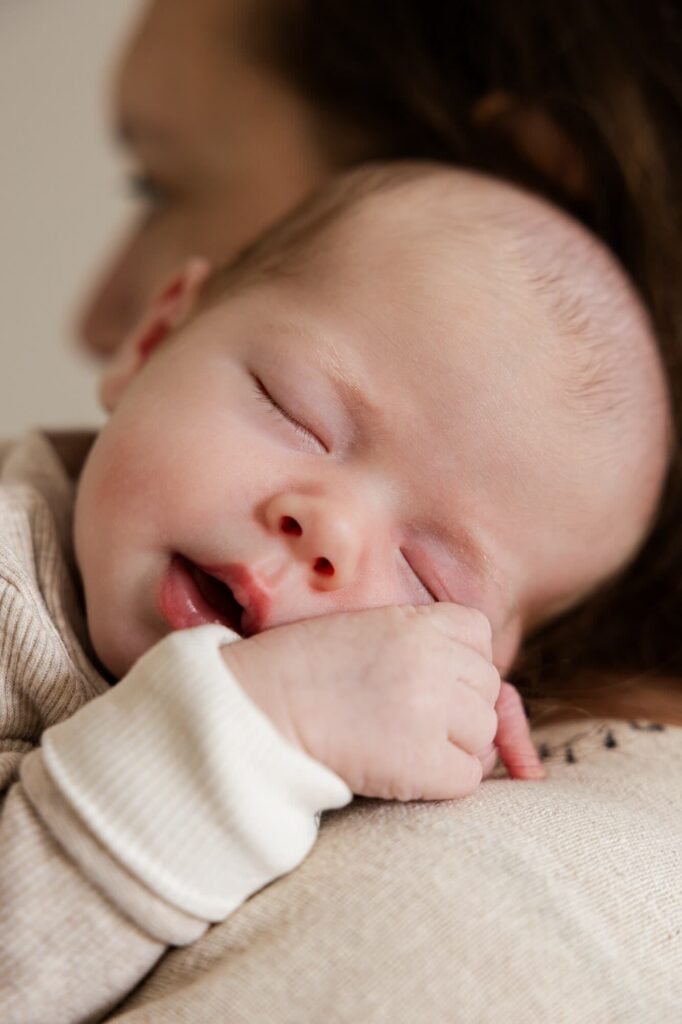 Pasgeboren baby slaapt op schouder van mama tijdens newbornshoot