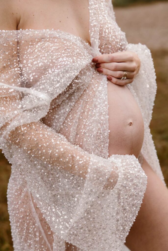 Vrouw in doorzichtige kimono met glitters tijdens zwangerschapsshoot