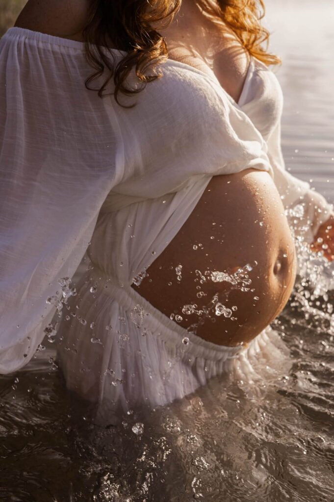 Close-up van zwangere vrouw in witte jurk in het water